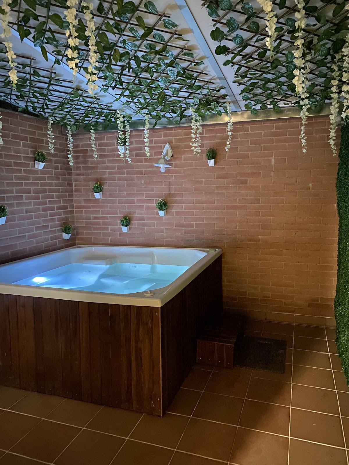 Sala del jacuzzi de Amarilis, con enredaderas de flores blancas y muro de ladrillo